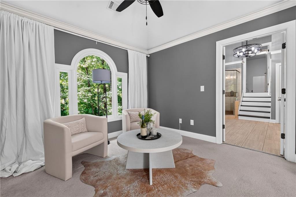 Furnished sitting area with an arched window, two chairs, and a doorway to a tiled bathroom.