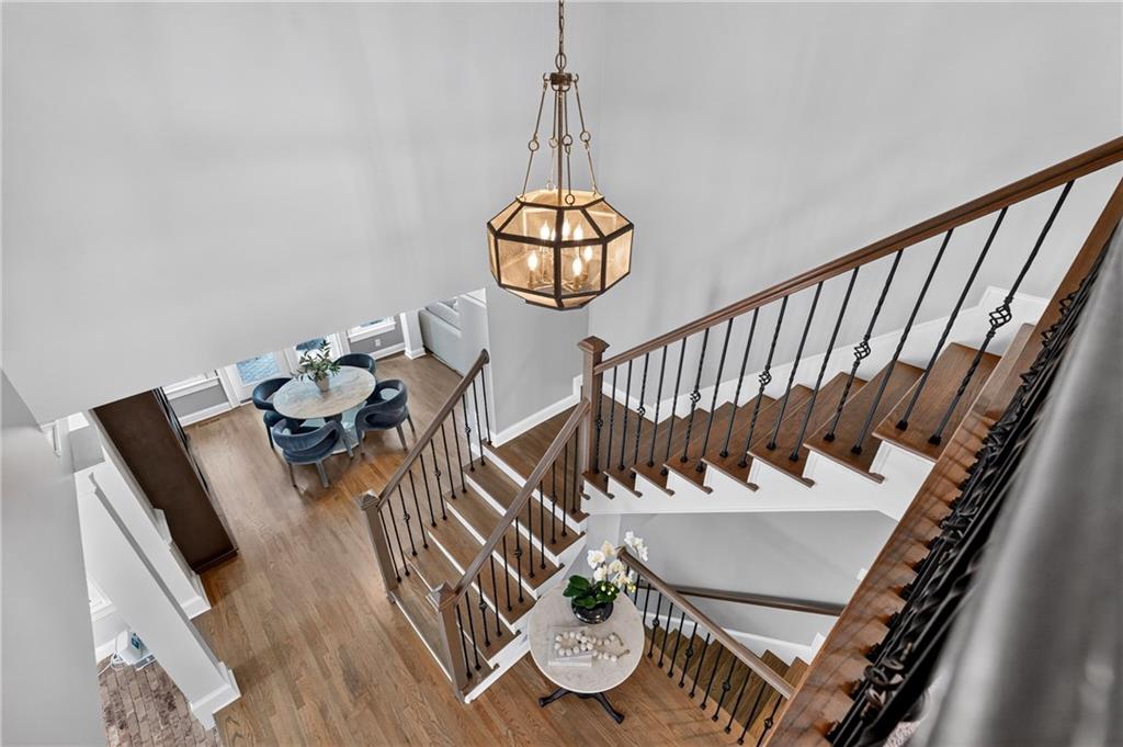 Foyer with a sweeping wood staircase, black metal railings, and a geometric chandelier.