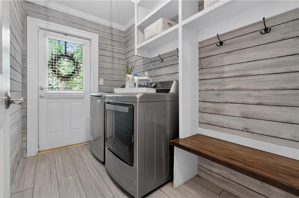 Laundry room with washer and dryer, gray plank walls, and a built-in wood bench.