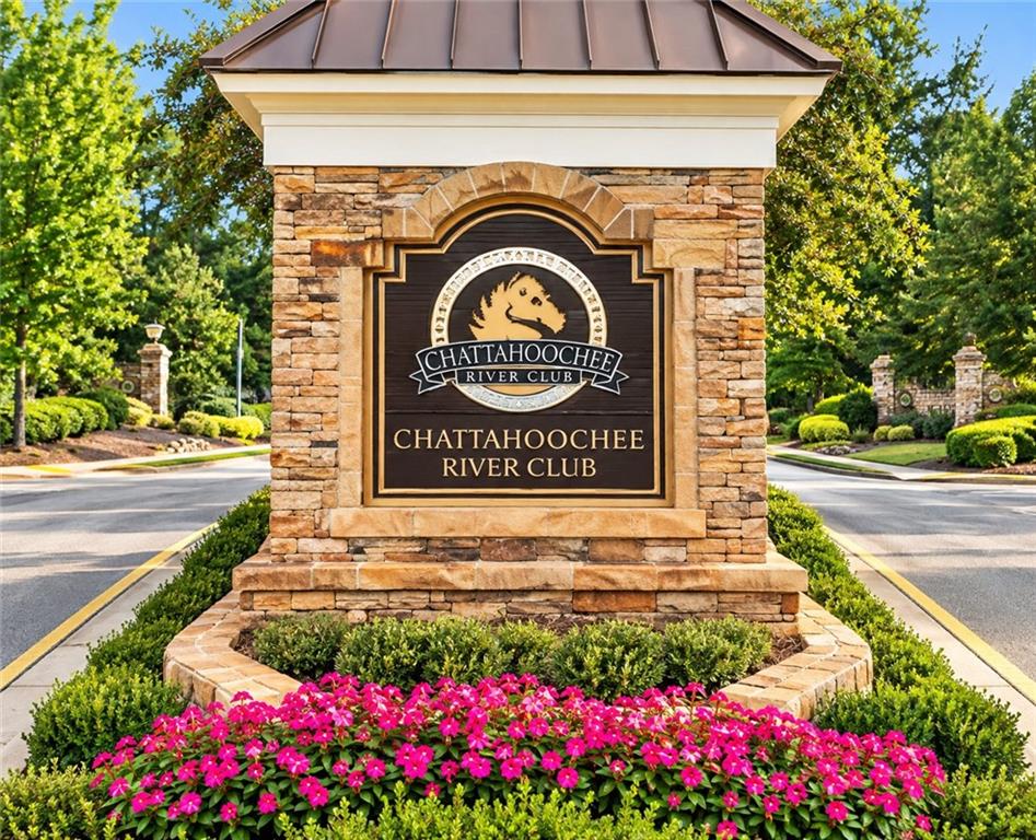Chattahoochee River Club entrance sign framed by stonework and bright pink flowers.