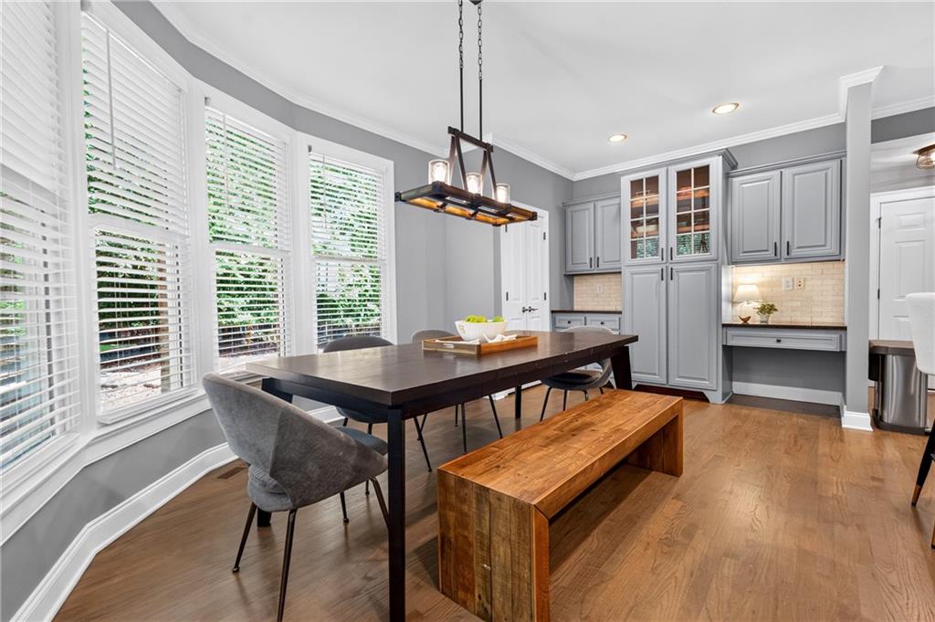 Dining area with a dark wood table, rustic bench, large windows, and gray built-in cabinetry.