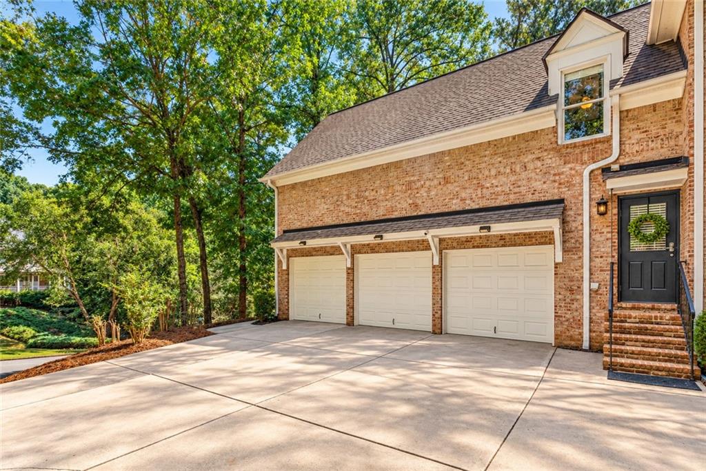 Brick home with three garage doors, a broad driveway, and a black front door.