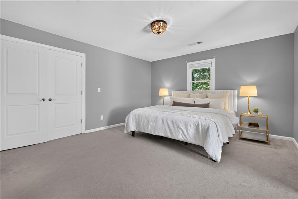 Staged bedroom with a large white bed, gray walls, and white paneled double doors.