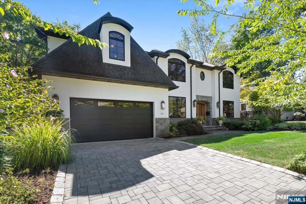 White two-story house with arched windows, an attached garage, and a broad paved driveway.