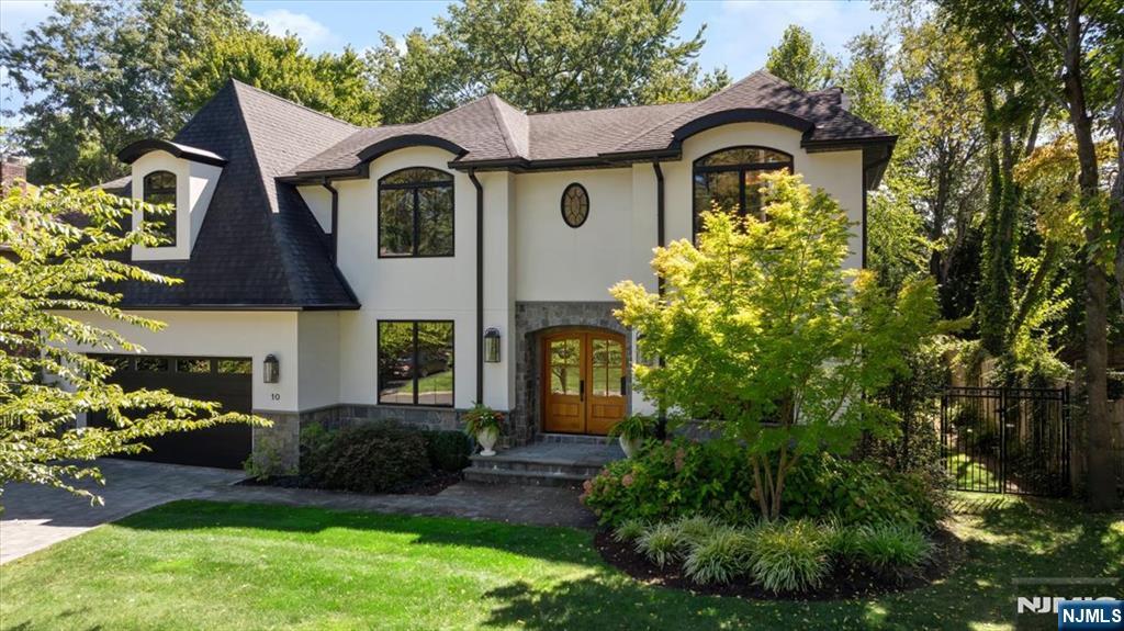 Two-story white house with dark trim, a stone-accented entrance, and landscaped front garden.