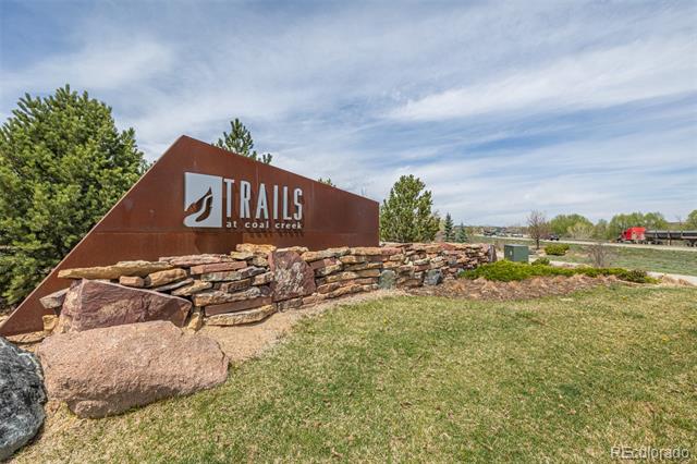 Trails at Coal Creek neighborhood entrance sign above a stone wall and landscaped grass.