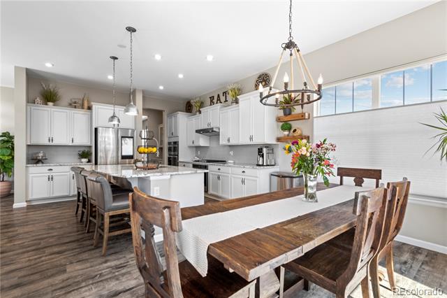 Bright kitchen and dining area with white cabinets, a large island, and a long wood dining table.