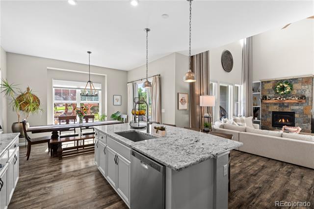 Open-plan kitchen with a large stone island, dining area, and living room fireplace.