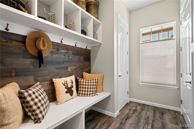 Mudroom with a built-in bench, coat hooks, cubbies, and a dark wood accent wall.