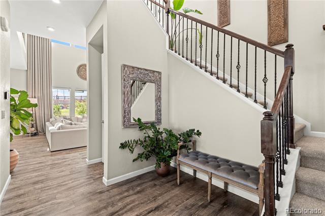 Entry foyer with dark wood staircase, tufted bench, and view into bright living room.