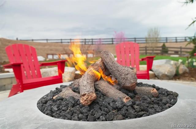 Patio fire pit with burning logs and red Adirondack chairs