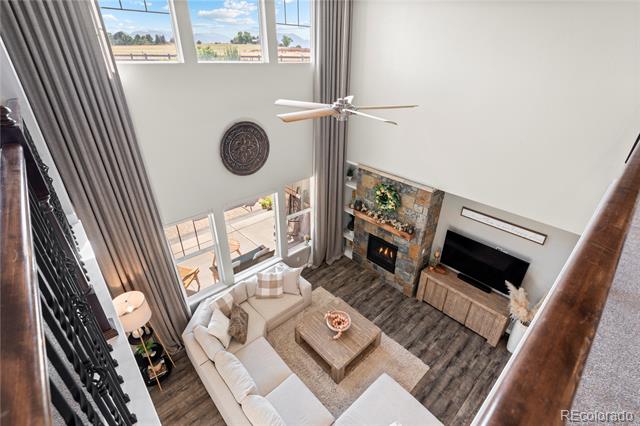 Double-height living room with a stone fireplace, tall windows, and a light sectional.