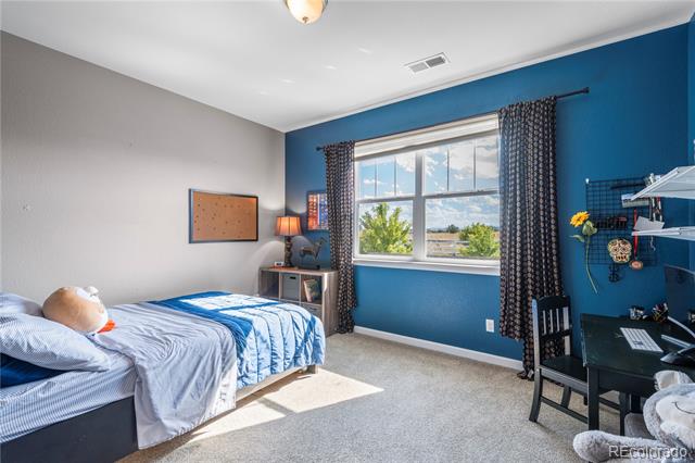 Bedroom with blue accent wall, large curtained window, and bed with blue and gray bedding.