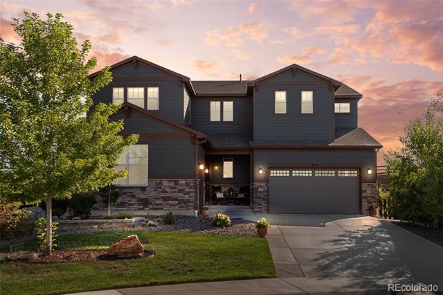 Two-story dark blue-gray house with stone accents and an attached garage at dusk.