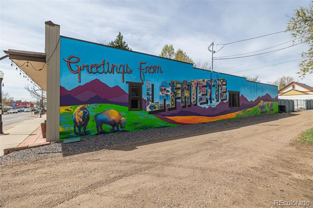 Exterior wall with a colorful Greetings From Lafayette mural featuring mountains and bison.