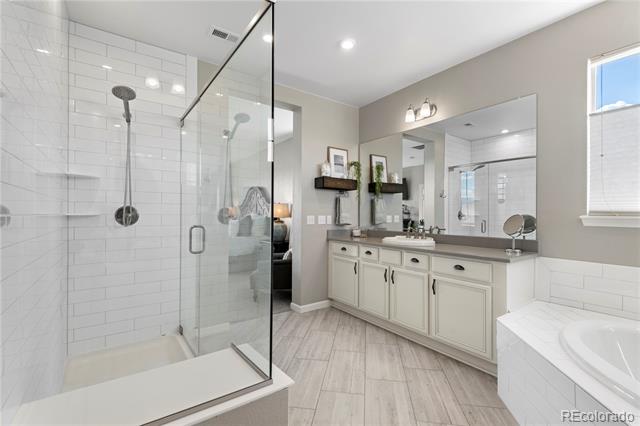 Bathroom with a glass-enclosed subway-tile shower, double vanity, and built-in soaking tub.