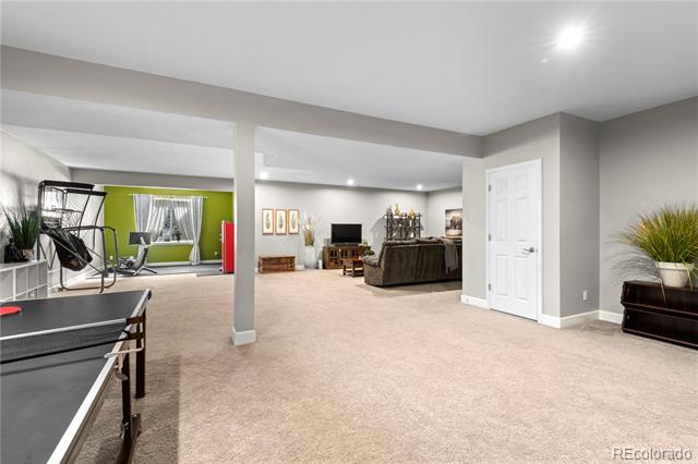 Finished basement recreation area with a ping-pong table, exercise equipment, and a TV seating area.