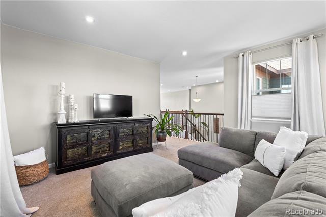 Living room with a gray sectional and ottoman, white pillows, and a dark rustic media console.