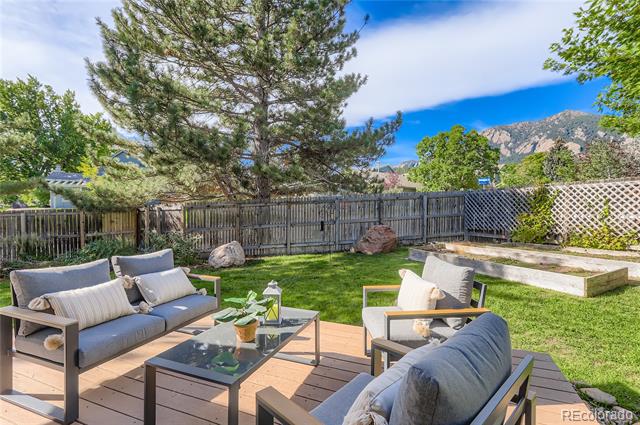 Backyard patio with cushioned seating, a lawn, raised garden bed, and mountain views.
