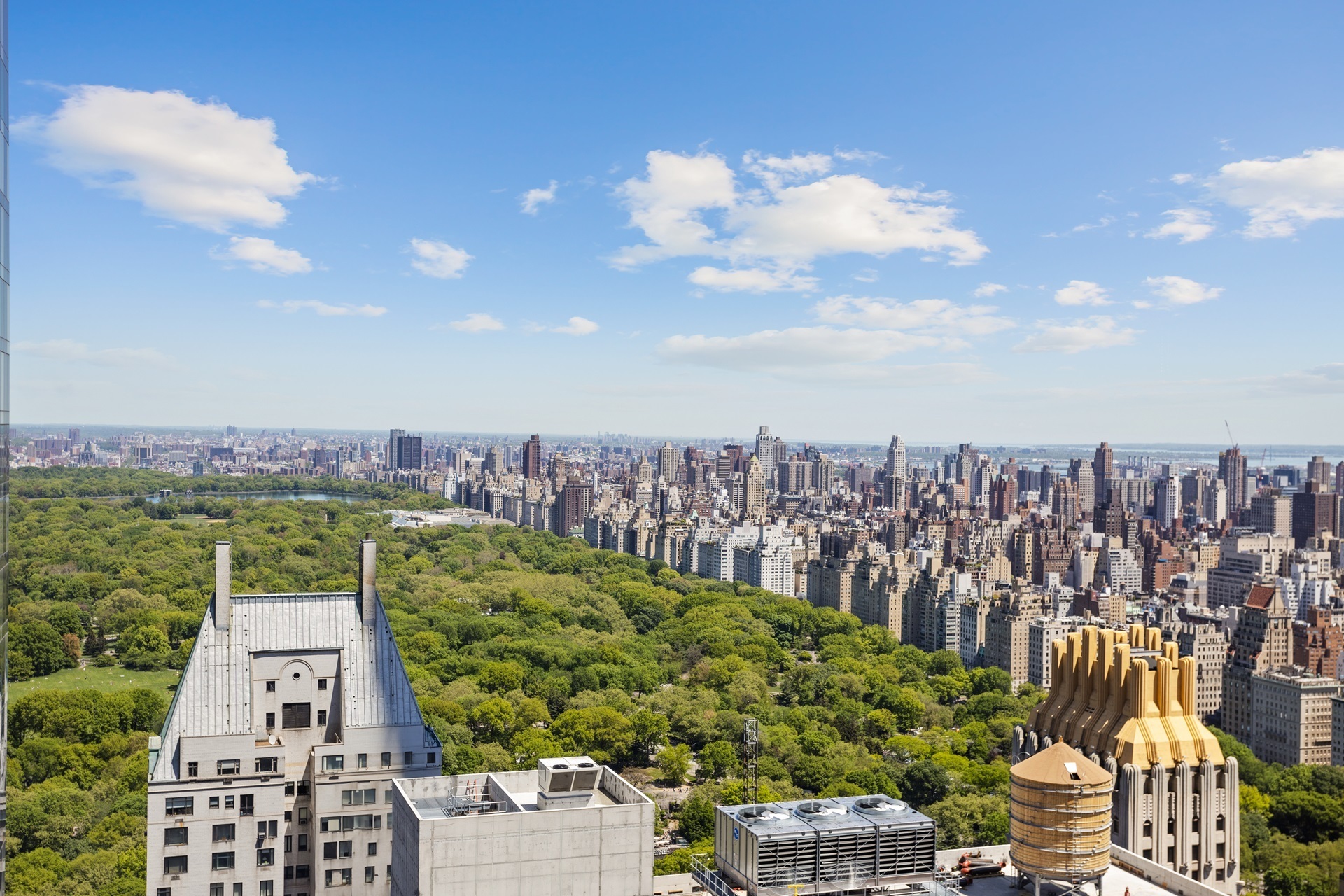 Manhattan skyline beyond Central Park, seen from above rooftops on a clear day.