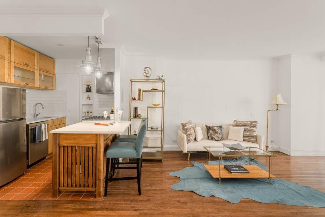 Open-plan kitchen and living area with a wood island, stainless appliances, and a cream sofa.