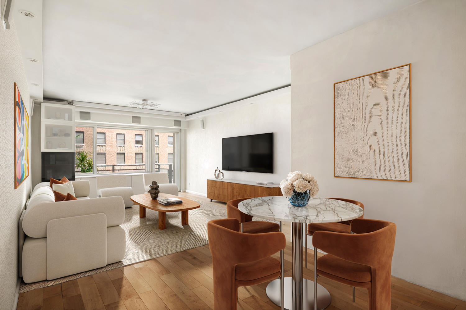 Open-plan living and dining room with cream seating, rust dining chairs, and large windows.