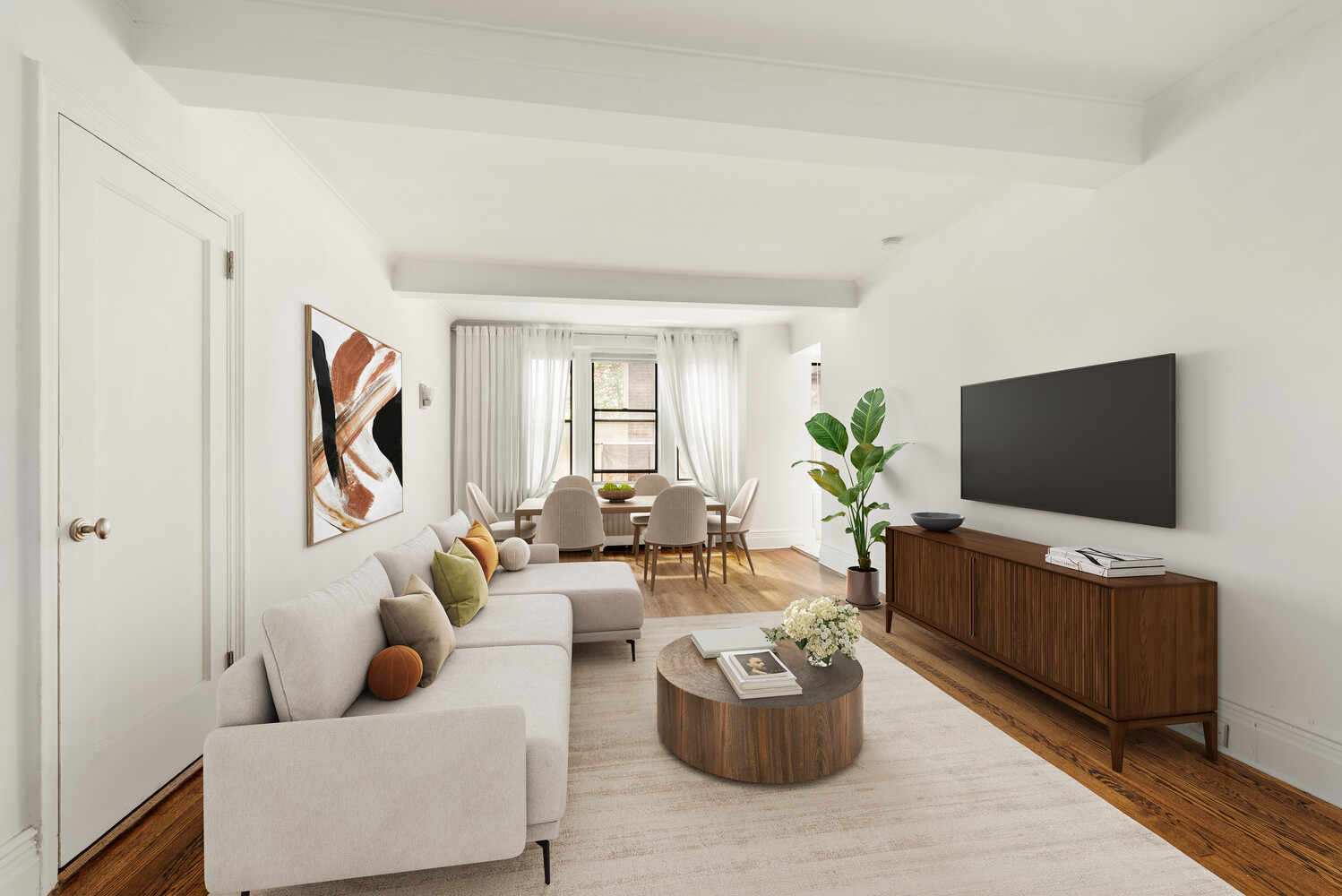 Bright condo living and dining room with a light sectional, round coffee table, and wood media console.