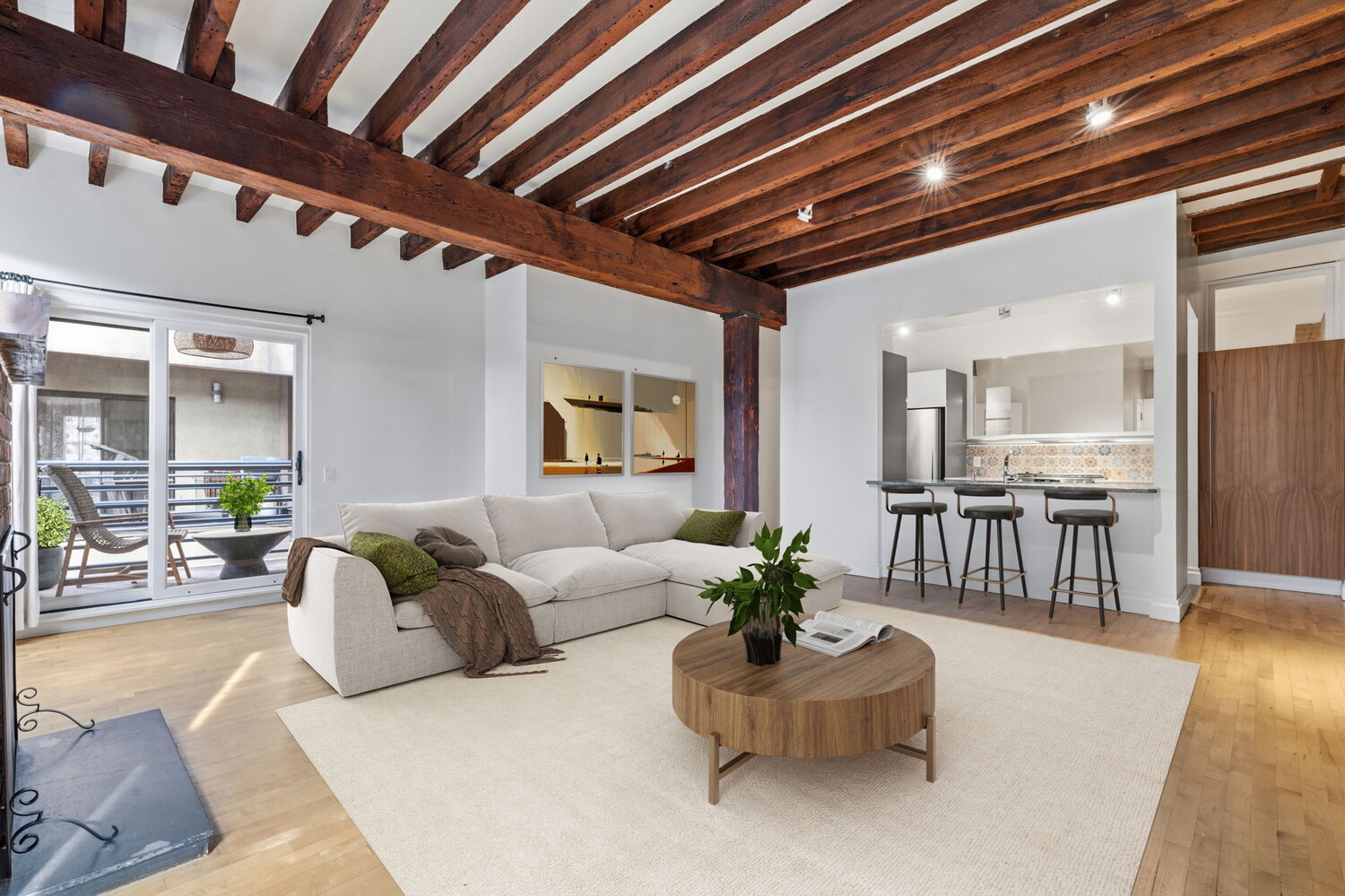 Living room with exposed timber beams, a white sectional, and an open kitchen with breakfast bar.