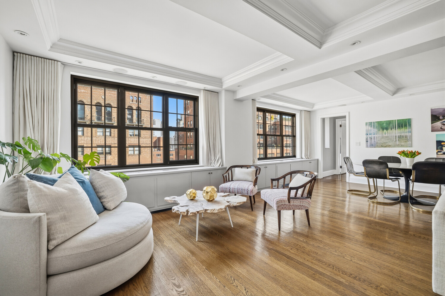 Living and dining area with oversized black-framed windows, white coffered ceiling, and hardwood floors.