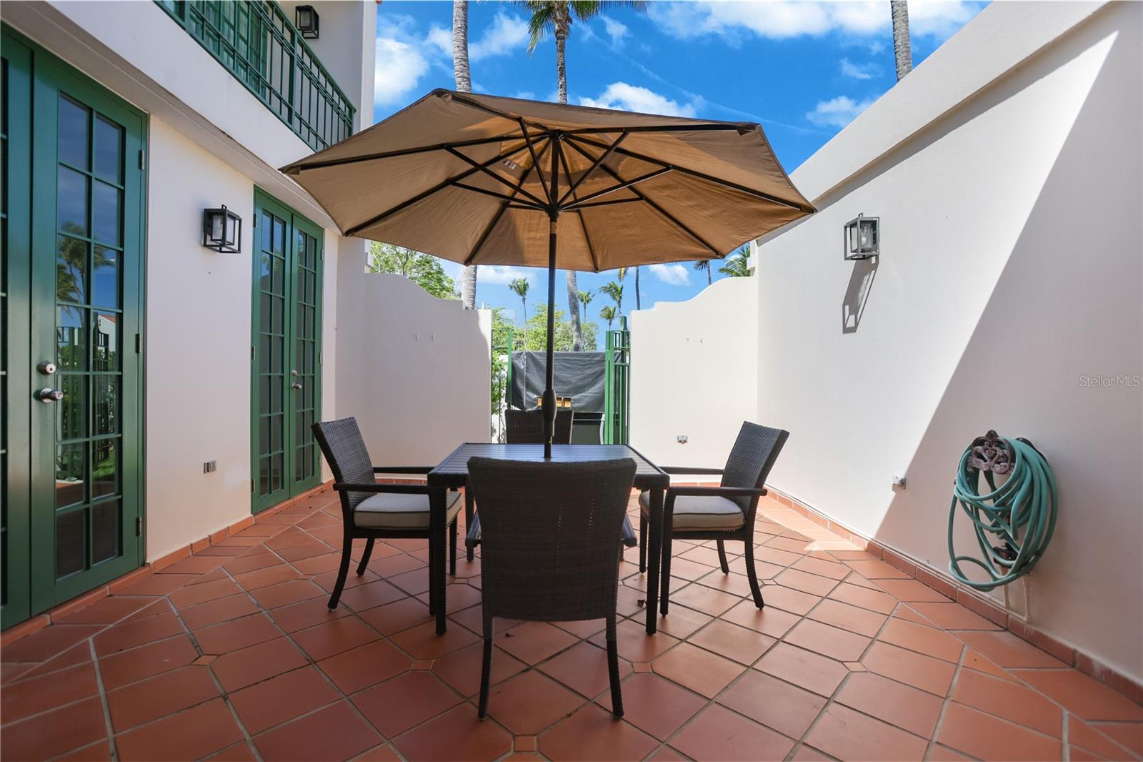 Furnished patio with terracotta tiles and dining set beneath a large umbrella.