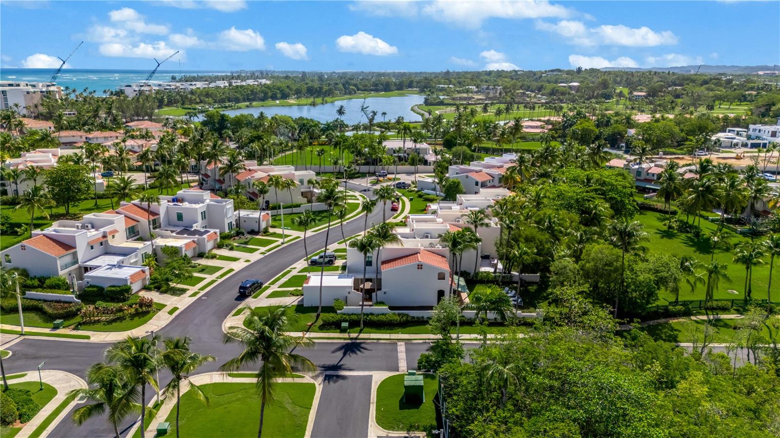 Aerial view of a tropical neighborhood, with the golf course, lagoon, and ocean in the distance.