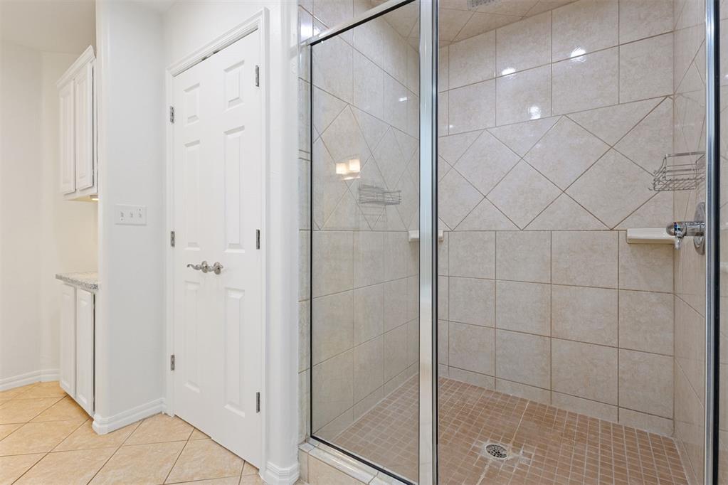 Bathroom with a glass-enclosed walk-in shower and beige tile walls.