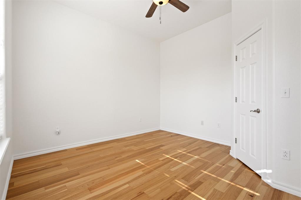 Vacant bedroom with hardwood floors and a ceiling fan.