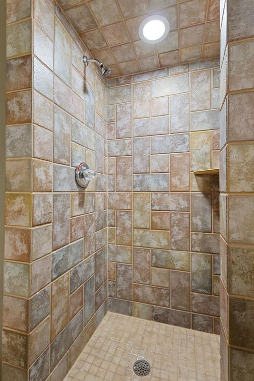 Tiled walk-in shower with a recessed niche and stone-look walls.
