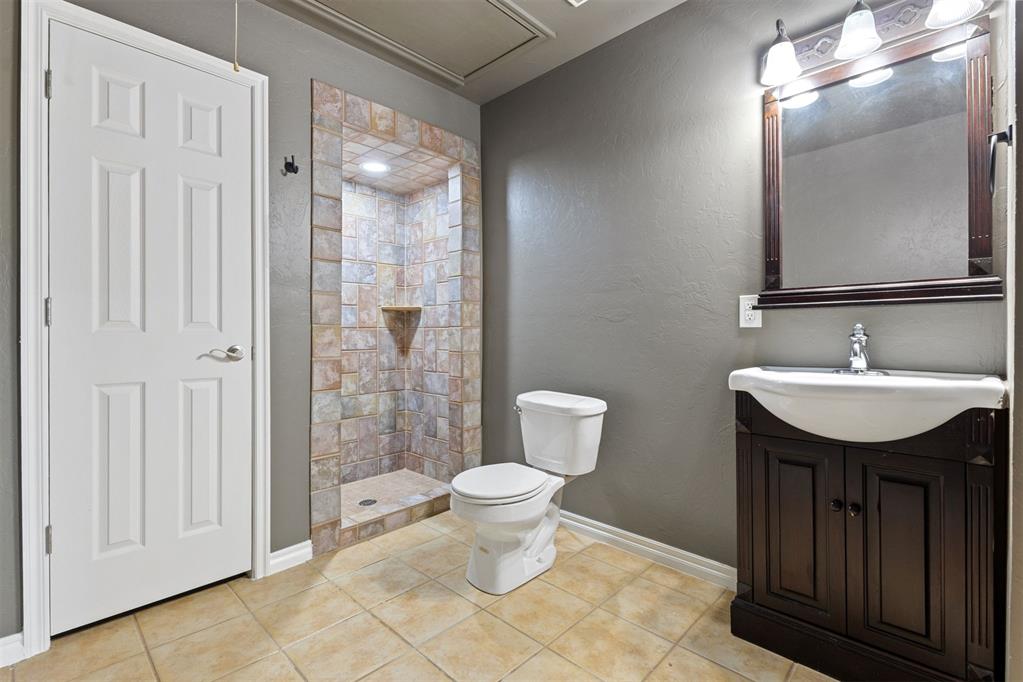 Bathroom with a multicolored tiled walk-in shower and dark wood vanity.