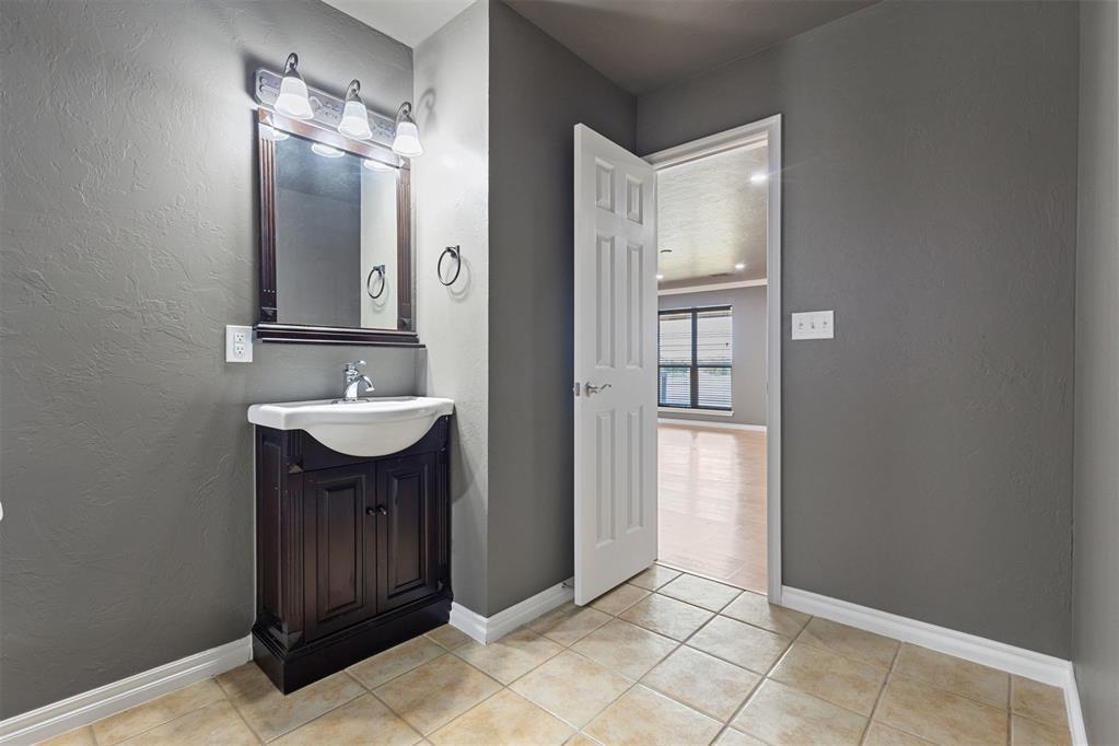 Bathroom with dark wood vanity and open doorway to a bright room.