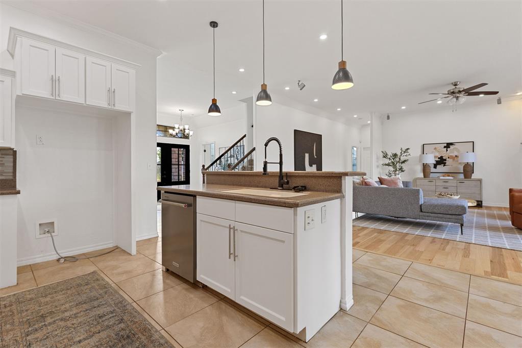Open-plan kitchen with a large island and pendant lights beside a furnished living area.
