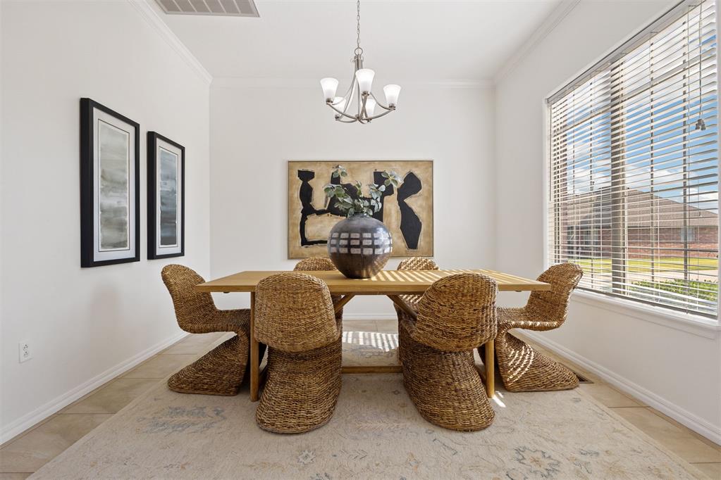 Dining room with a wooden table, woven wicker chairs, and a large sunlit window.