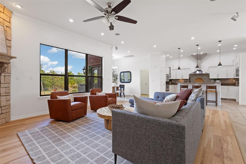 Open-plan living room with a gray sectional, rust-colored armchairs, and large windows overlooking trees.