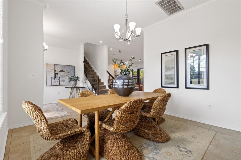 Dining room with a wooden table, woven chairs, and a staircase in the background.