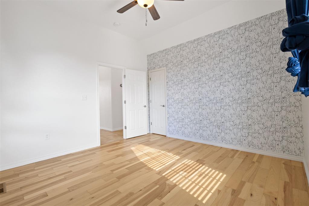 Empty bedroom with light hardwood floors and a wall covered in black-and-white animal-pattern wallpaper.