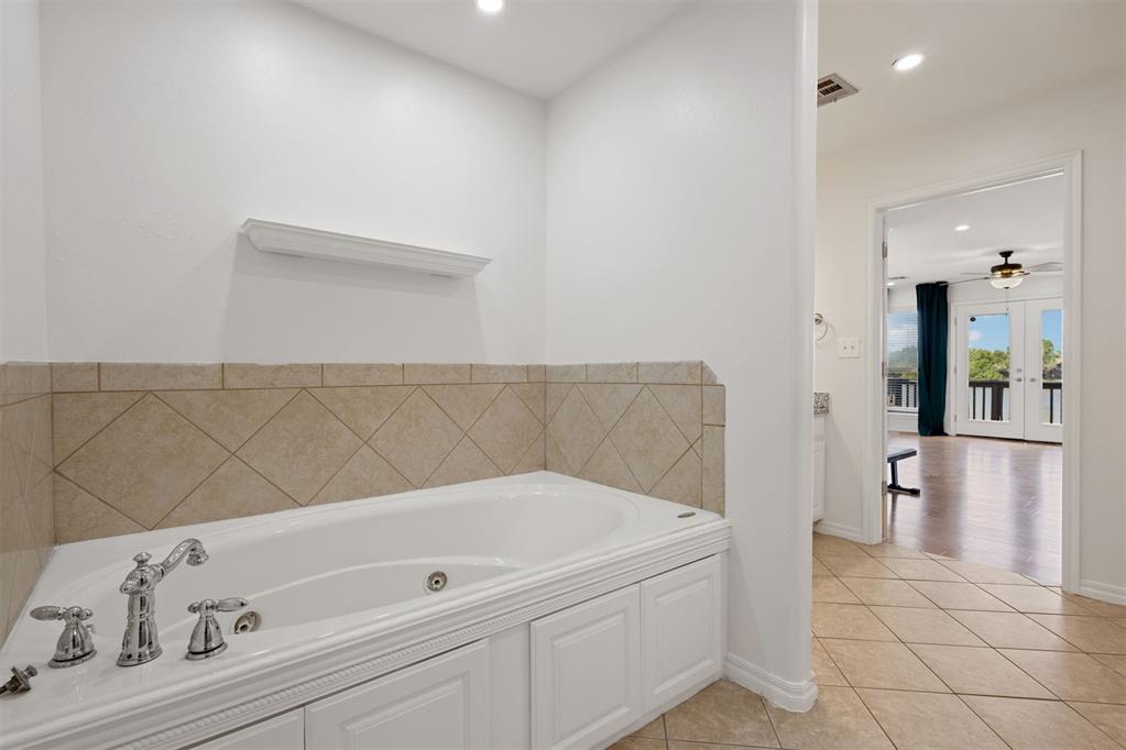 Bathroom with a white jetted tub, chrome fixtures, and beige tile backsplash.