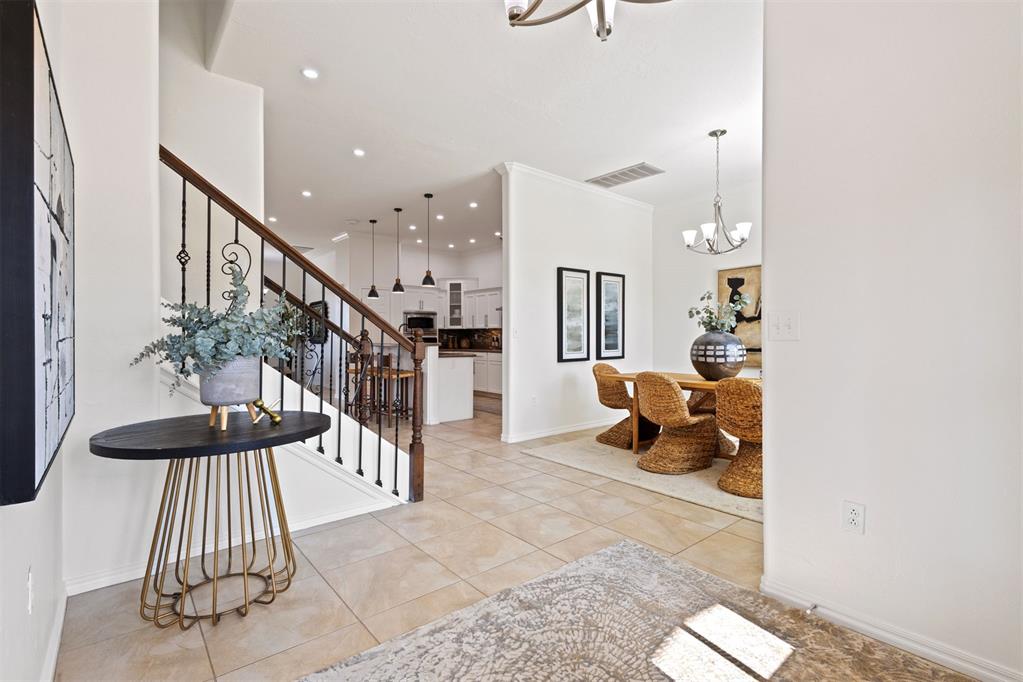 Tiled entry foyer with a dark wood staircase overlooking the dining area and kitchen.