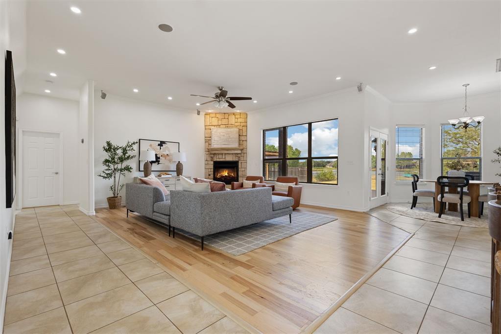 Open-plan living room with a gray sectional, stone fireplace, and large windows.