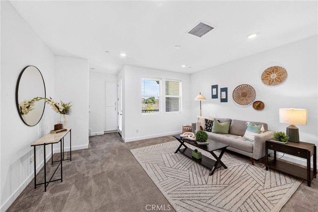Staged living room with a gray sofa, geometric rug, and woven wall decor.