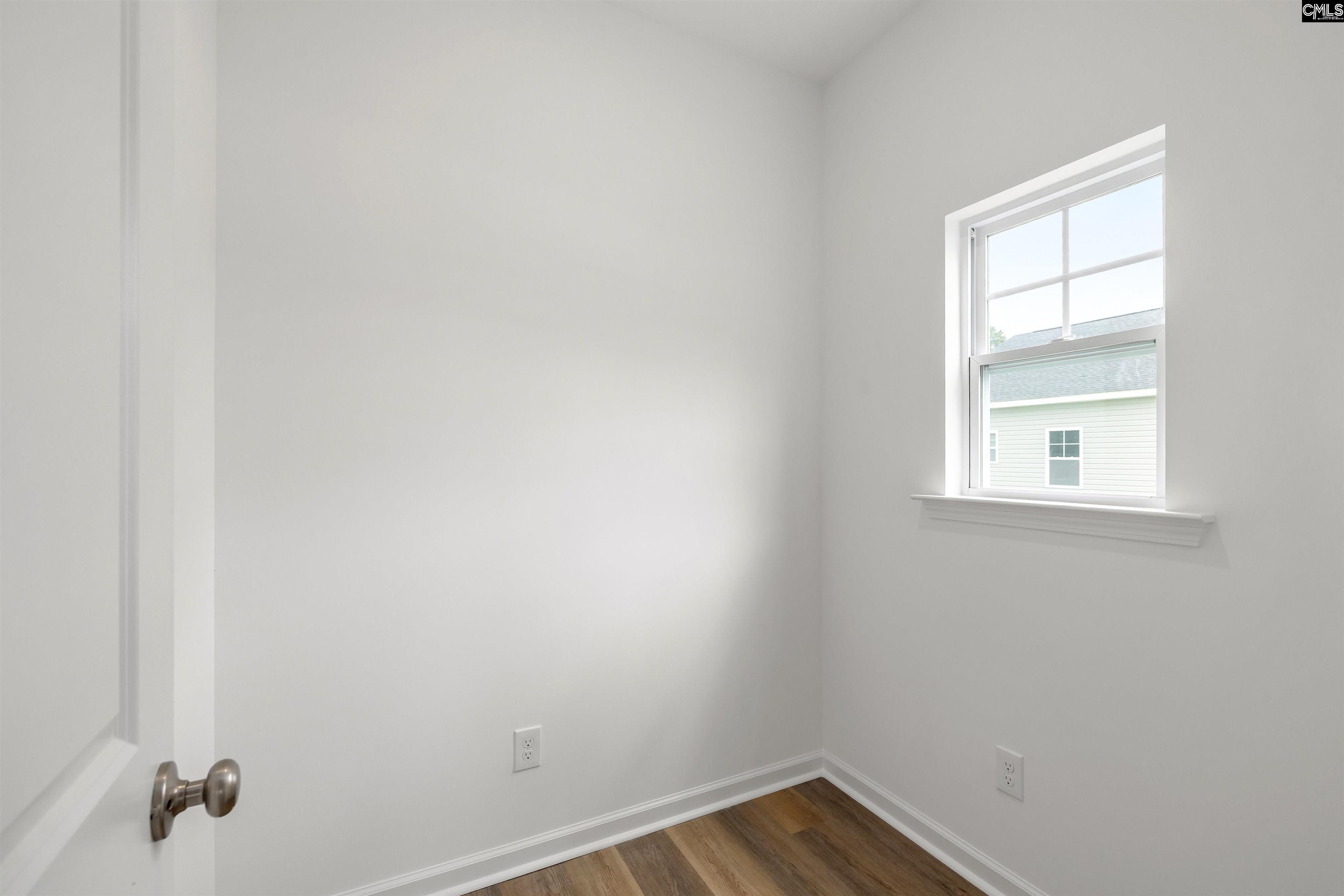 Vacant room with wood-look flooring, a single window, and a partially open door.