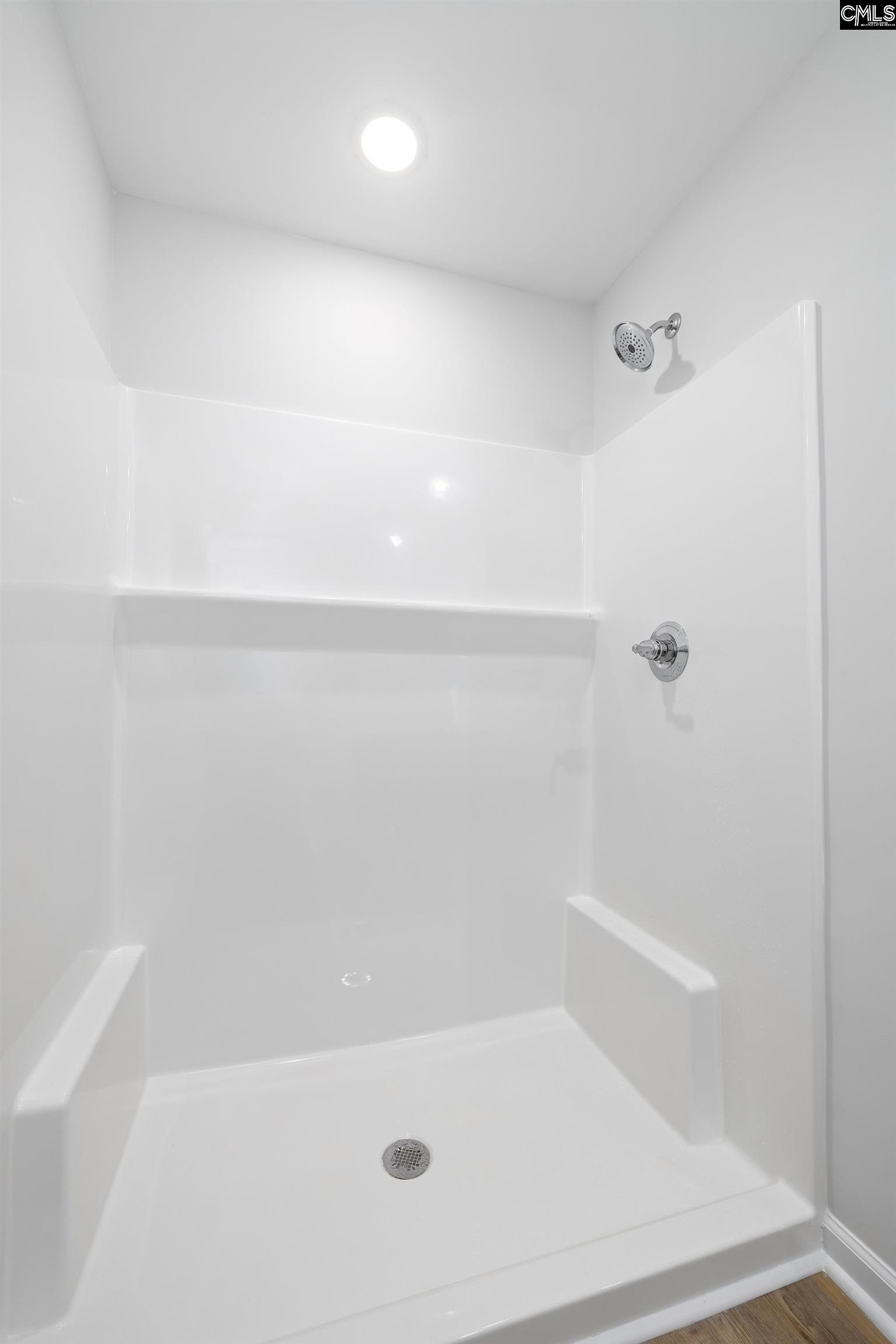 White walk-in shower with a built-in shelf and chrome fixtures.