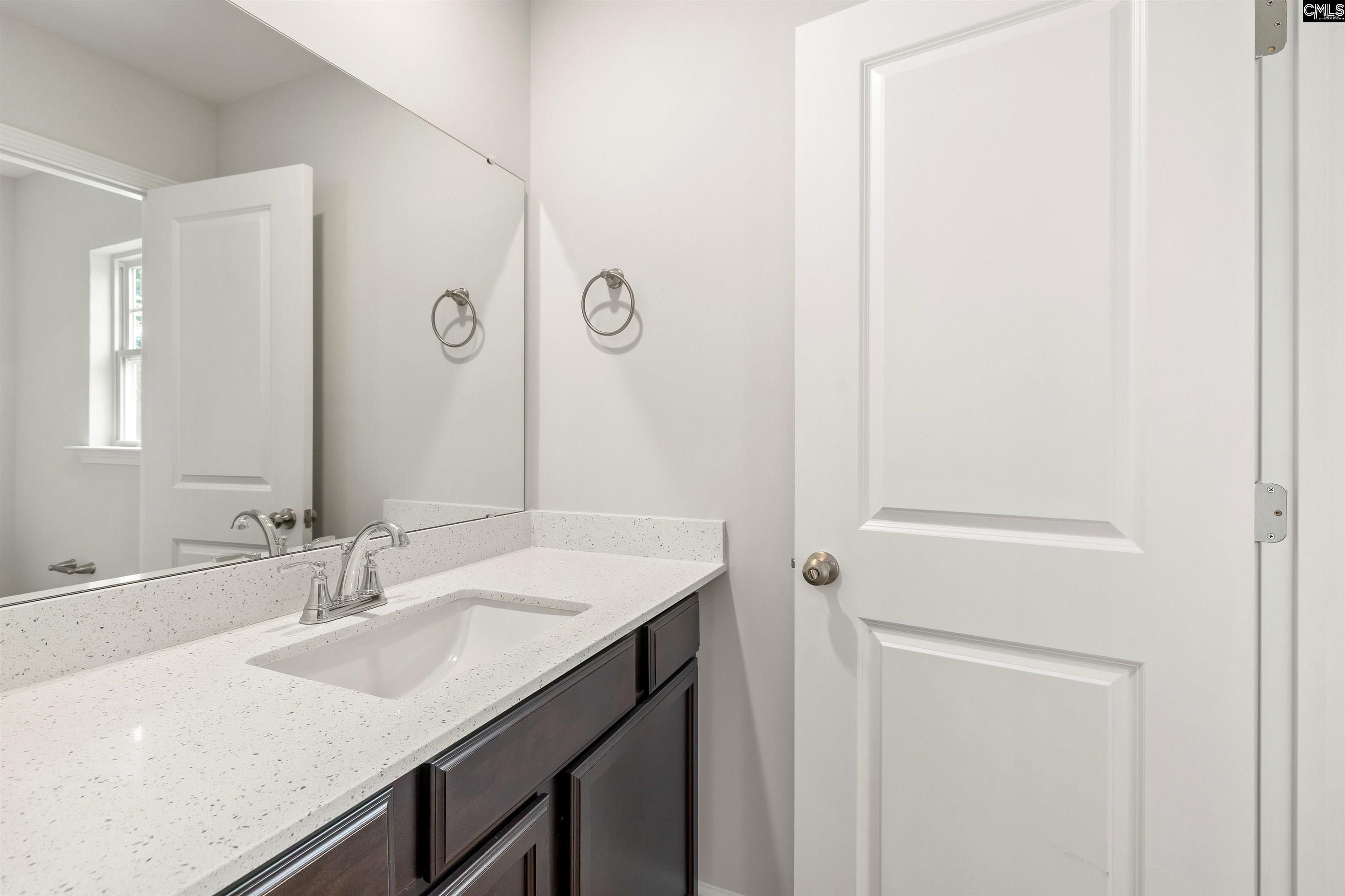 Bathroom vanity with a speckled white countertop, undermount sink, chrome faucet, and dark cabinets.