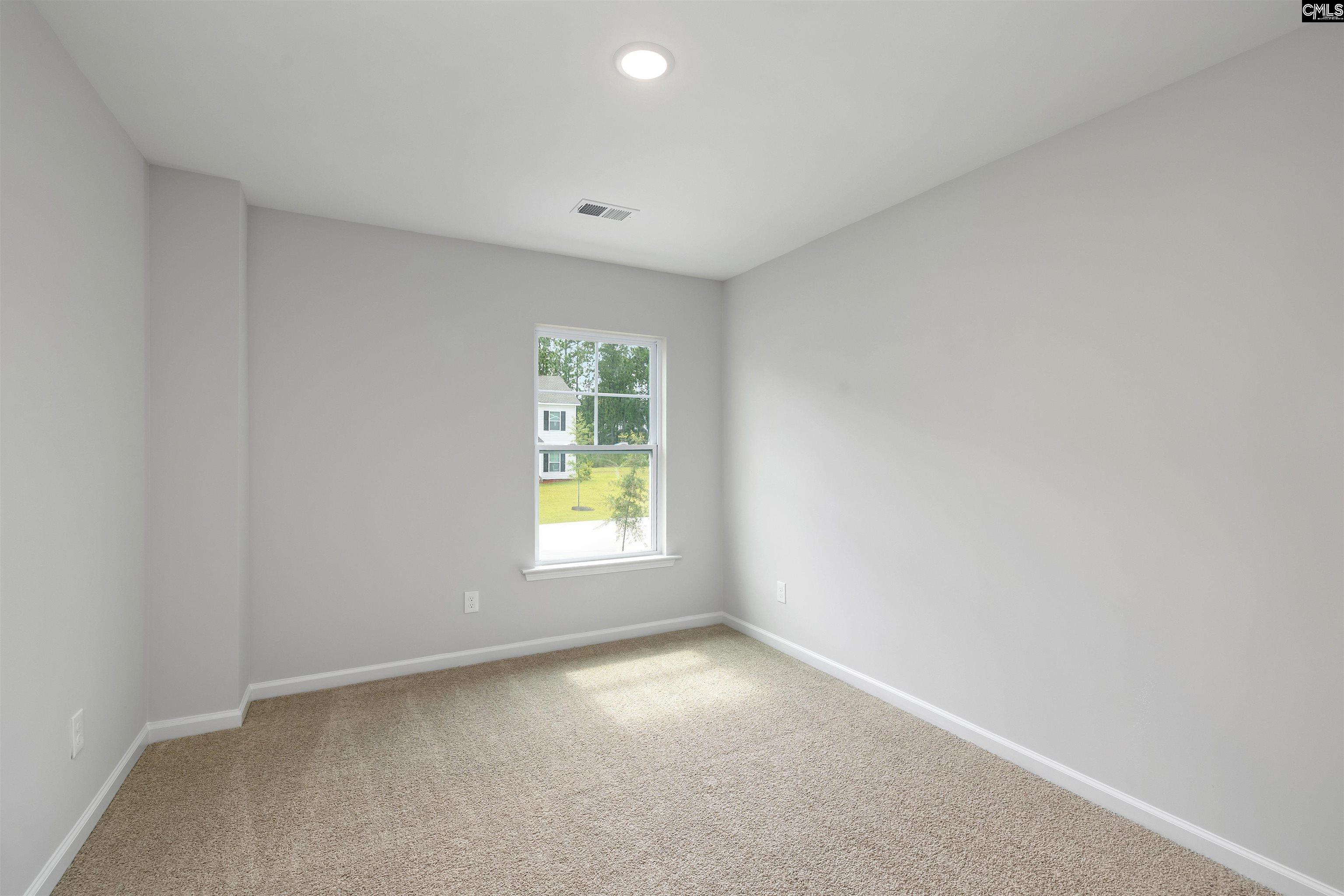 Empty carpeted bedroom with gray walls and a window overlooking the lawn.