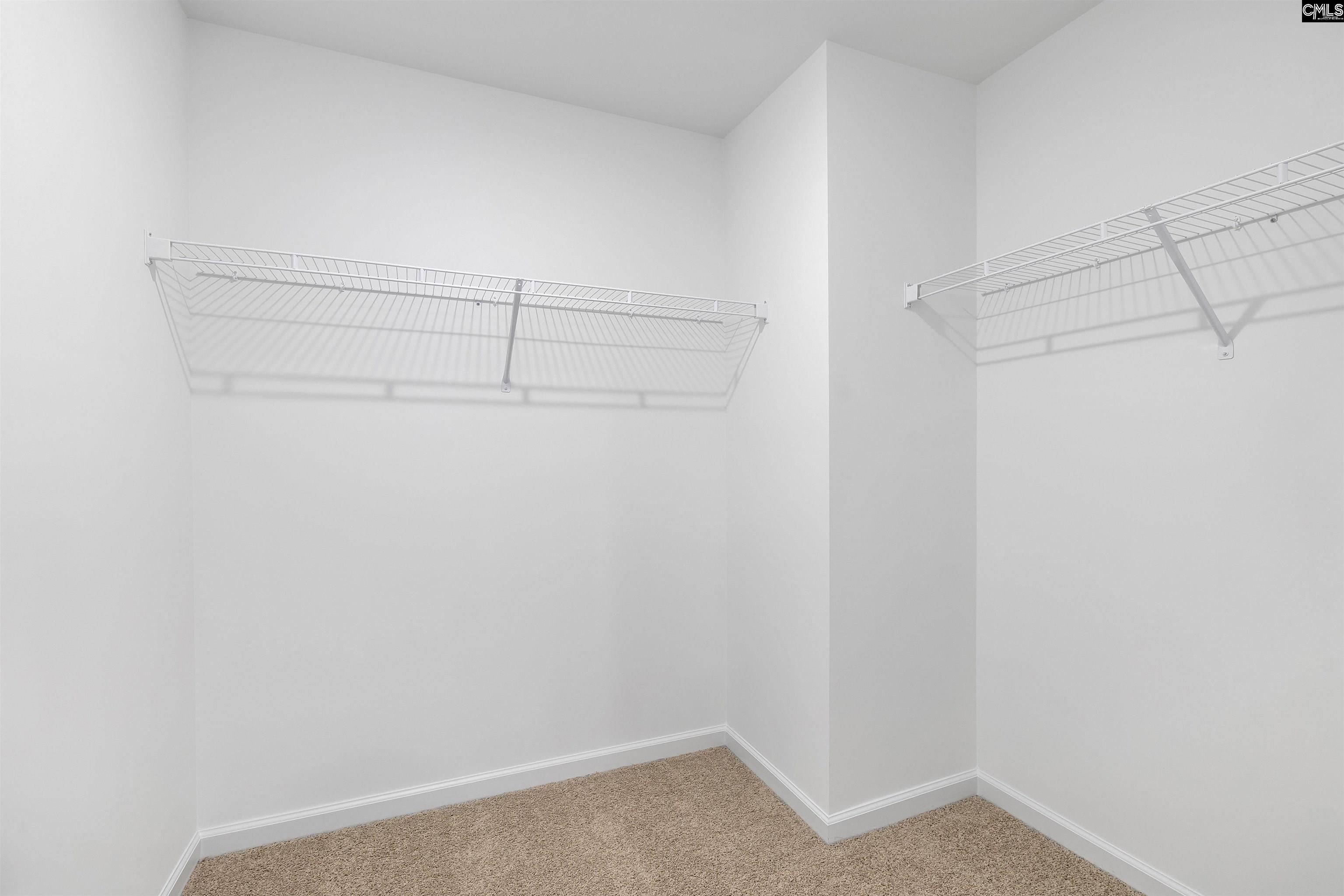 Empty walk-in closet with wire shelves and hanging rods on two walls.